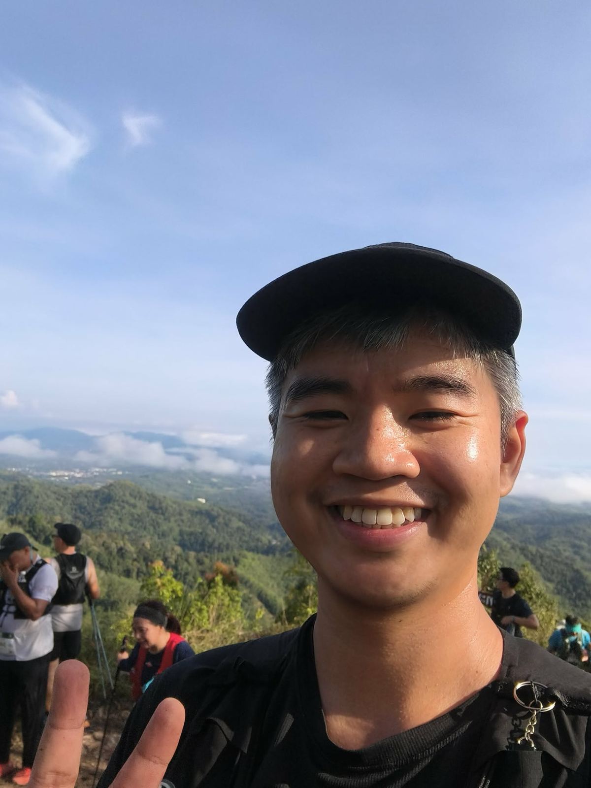 Folk smiling on a mountain top above the clouds