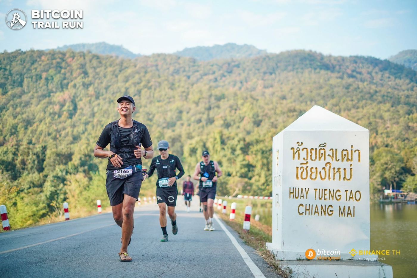 Folk running a mountain race past the Huay Tueng Tao sign in Chiang Mai